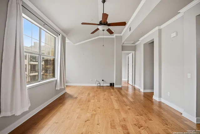 a view of empty room with wooden floor and fan