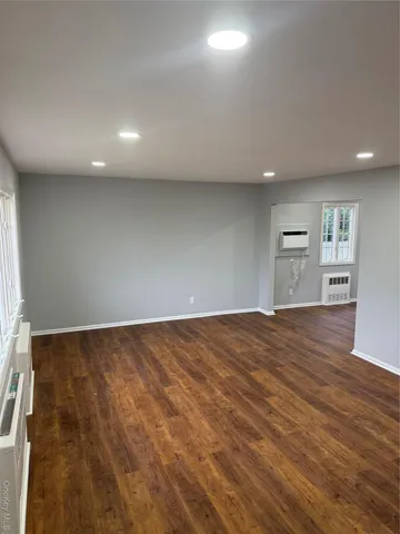 an empty room with wooden floor and natural light