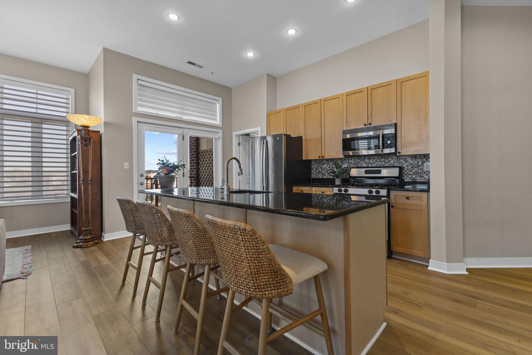 181 East Reed Avenue, Unit 411 Alexandria, VA 22305 - Photo 6 of 24 a kitchen with stainless steel appliances a dining table chairs and granite counter tops