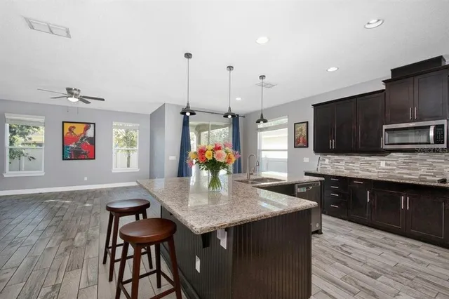 a kitchen with stainless steel appliances granite countertop a kitchen island hardwood floor sink stove dining table and chairs