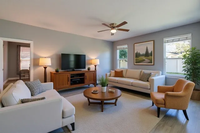 a living room with furniture a flat screen tv and a large window
