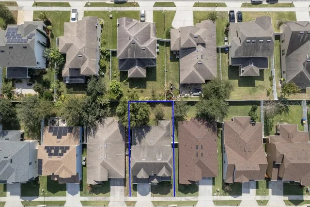 an aerial view of a house with a yard and large tree