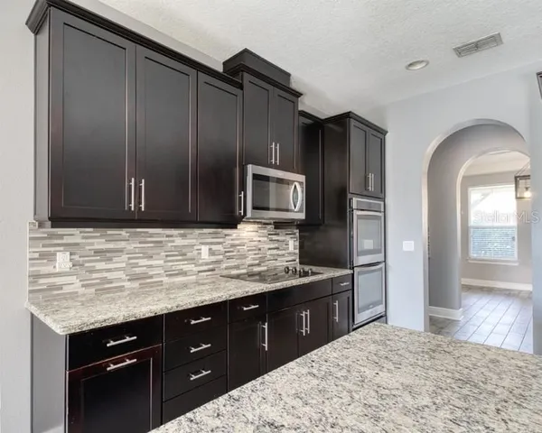 a kitchen with stainless steel appliances kitchen island granite countertop a sink stove and refrigerator