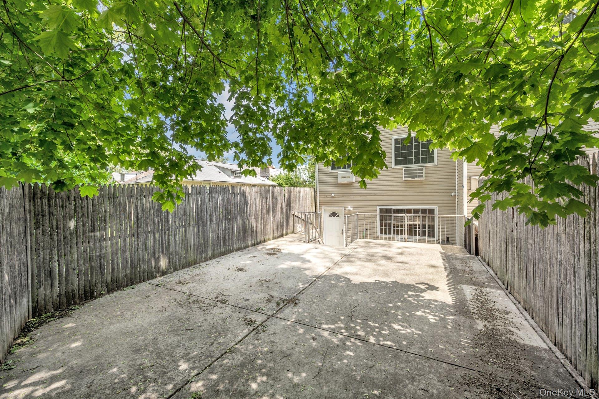 3313 Rombouts Avenue Bronx, NY 10475 - Photo 31 of 44 a backyard of a house with large trees and wooden fence