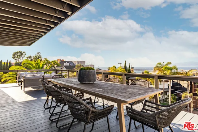 a roof deck with a dining table and chairs with wooden floor