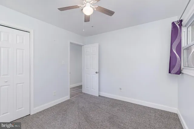an empty room with a ceiling fan and a window