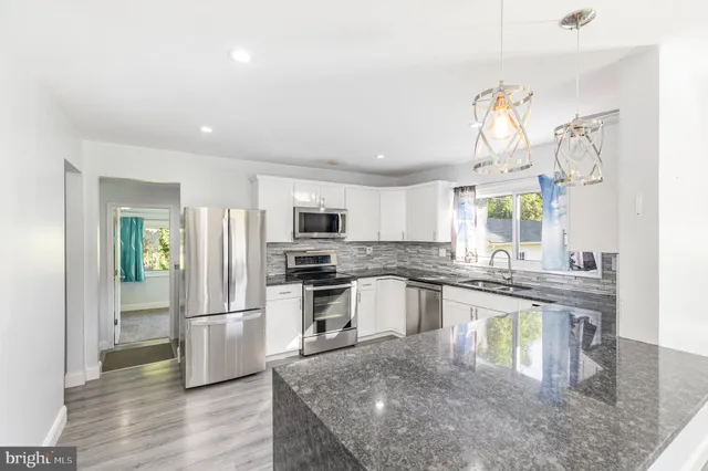 a kitchen with stainless steel appliances granite countertop a refrigerator a stove top oven a sink and dishwasher