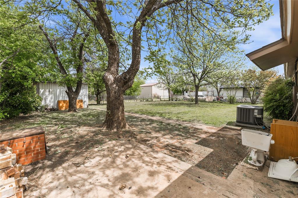 900 West 2nd Street Coleman, TX 76834 - Photo 28 of 28 a view of a backyard with table and chairs and a barbeque with potted plants and large trees
