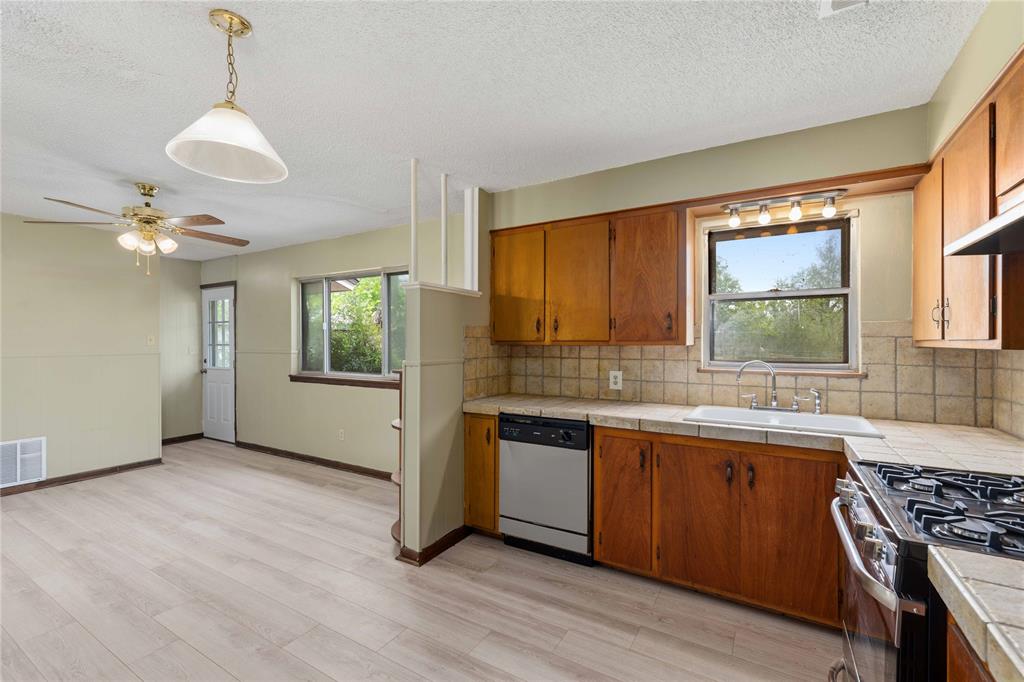 900 West 2nd Street Coleman, TX 76834 - Photo 9 of 28 a kitchen with stainless steel appliances granite countertop a sink a stove a refrigerator and island with wooden floor