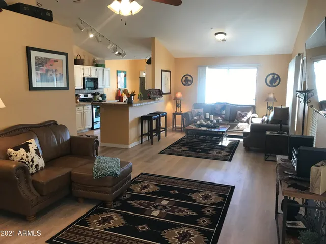 a living room with furniture kitchen view and a window
