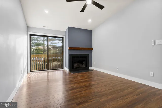 an empty room with wooden floor fireplace and windows