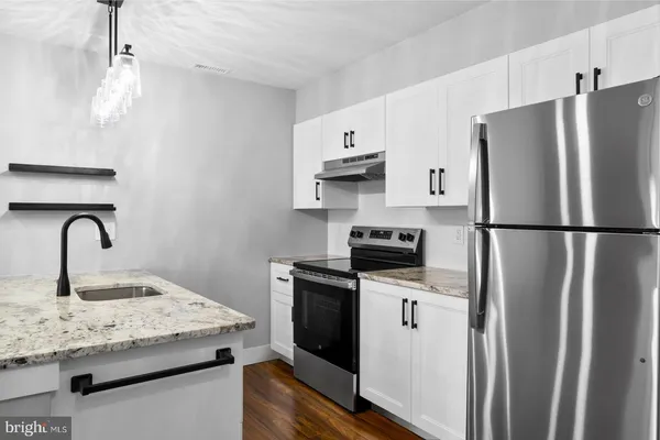 a kitchen with stainless steel appliances granite countertop a refrigerator a stove a sink dishwasher and a refrigerator with wooden floor