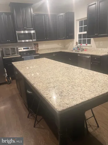 a kitchen with kitchen island granite countertop a sink a stove and a wooden cabinets