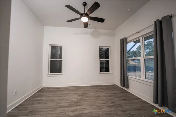 a view of an empty room with a window and wooden floor