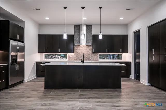 a large kitchen with stainless steel appliances wooden cabinets and a wooden floor