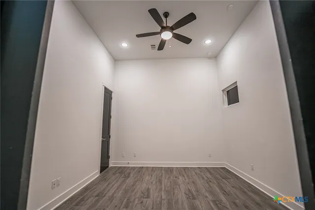an empty room with wooden floor and a ceiling fan