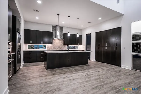 a kitchen with stainless steel appliances kitchen island granite countertop a refrigerator and a stove top oven