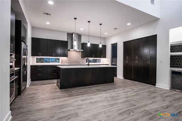 a kitchen with stainless steel appliances kitchen island granite countertop a refrigerator and a stove top oven