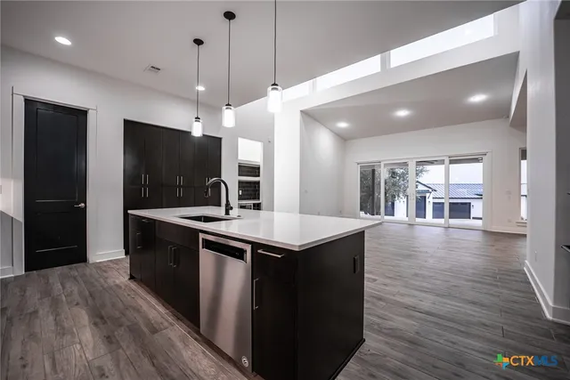 a kitchen with stainless steel appliances granite countertop a sink a stove and a wooden floors