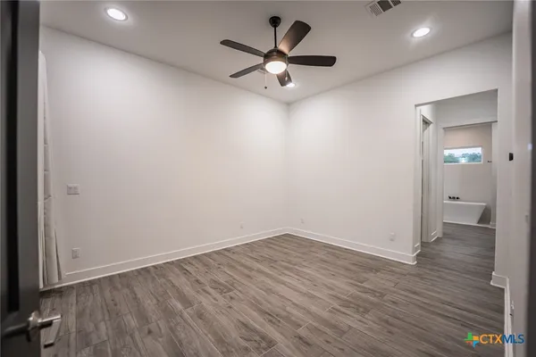 an empty room with wooden floor and a ceiling fan