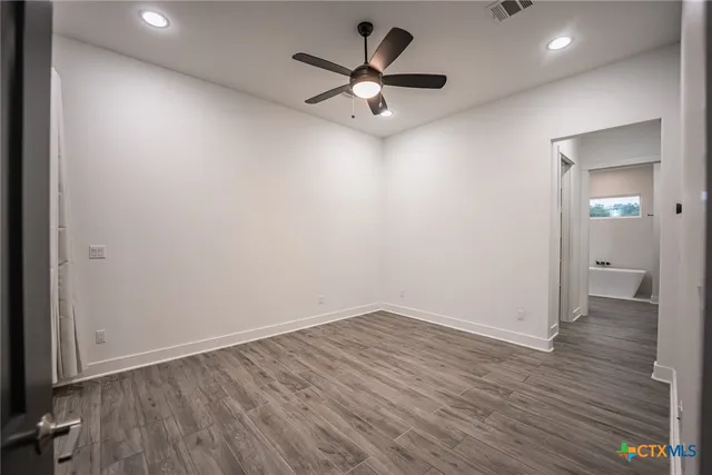 an empty room with wooden floor and a ceiling fan