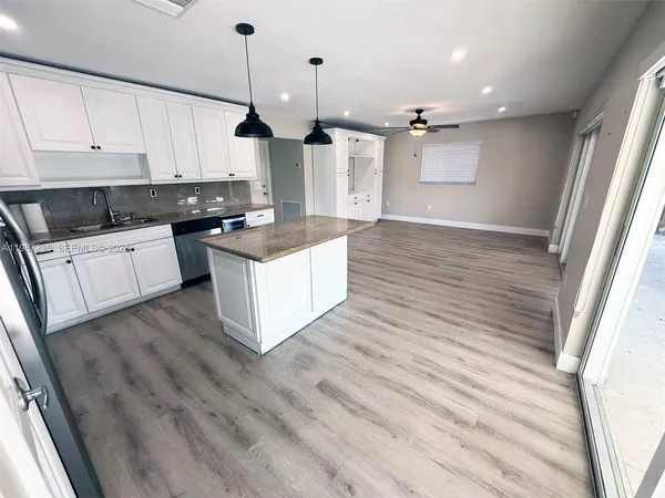 a kitchen with kitchen island wooden floors appliances and cabinets