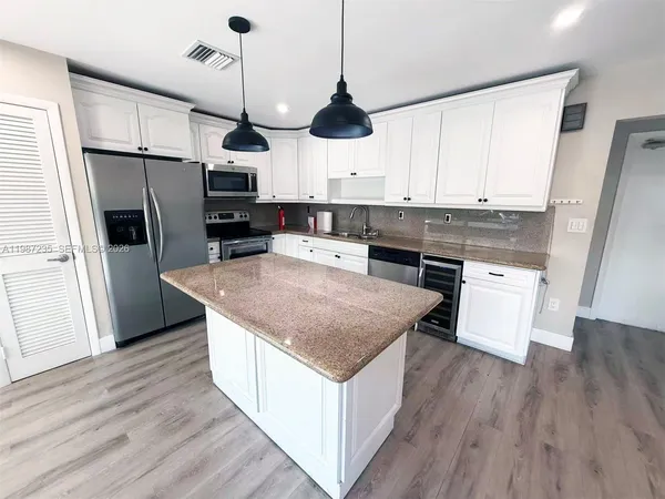 a kitchen with stainless steel appliances granite countertop a refrigerator a stove a sink and a wooden floors