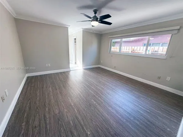 a view of an empty room with a window and wooden floor