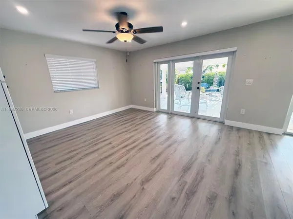 a view of an empty room with a window and wooden floor