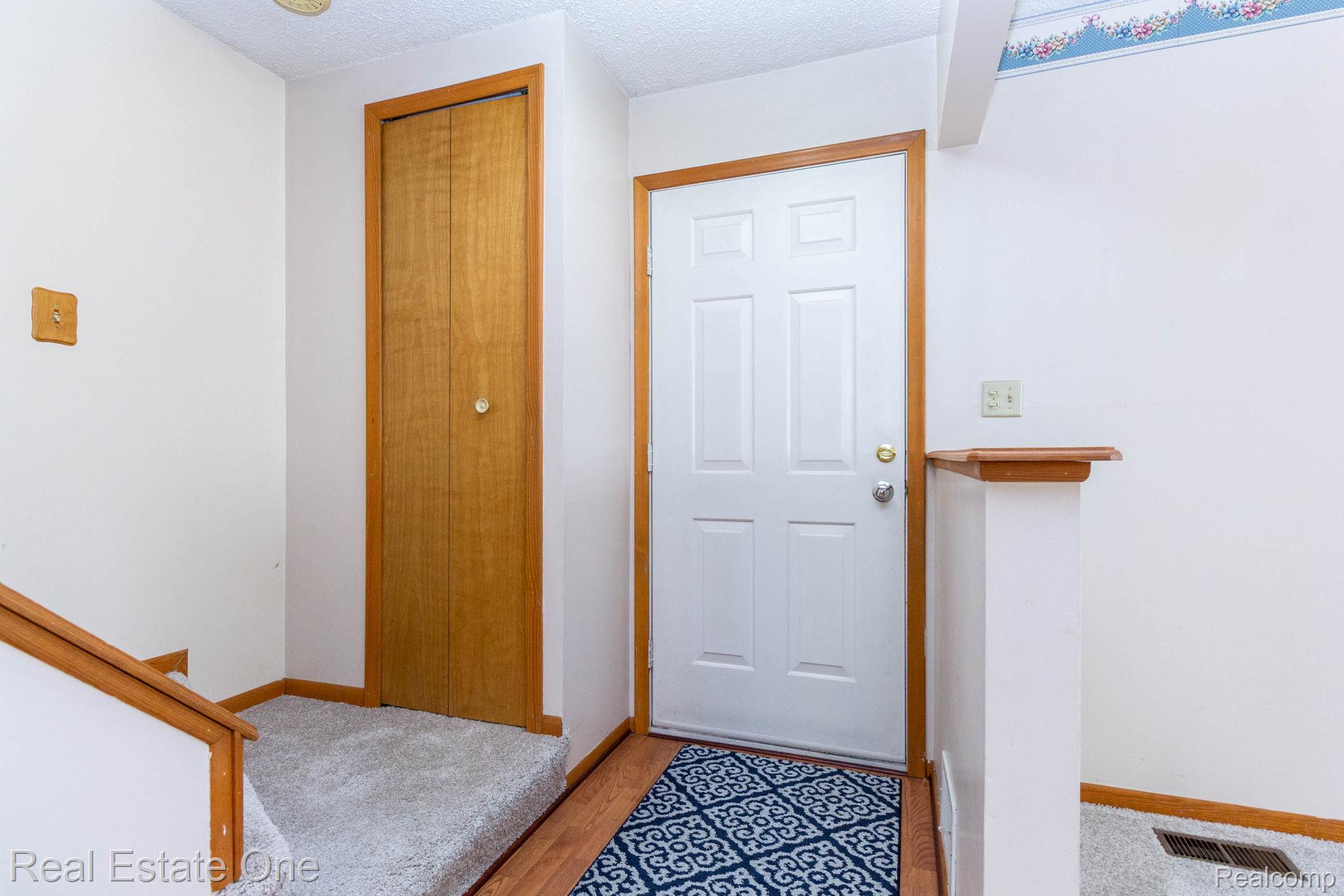 13912 Clinton River Road Sterling Heights, MI 48313 - Photo 5 of 43 Entryway featuring a white paneled door with wood trim, wood-finish flooring, and light-toned walls