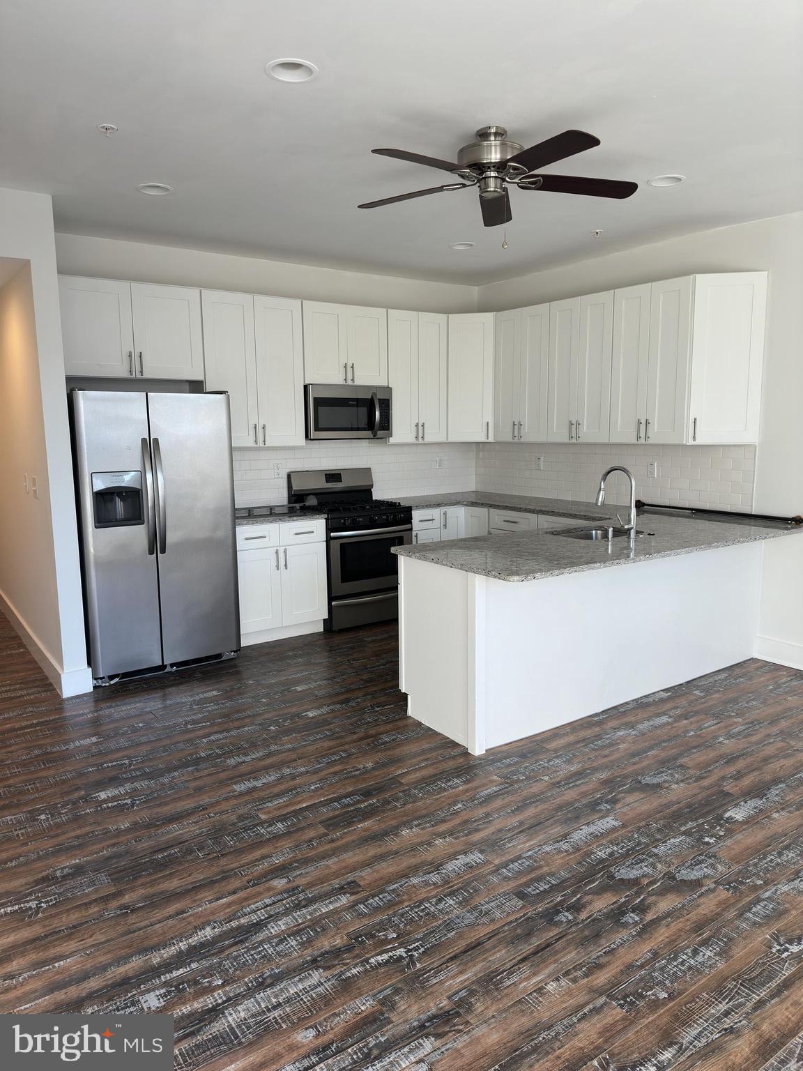 2206 North Front Street, Unit 2B Philadelphia, PA 19133 - Photo 17 of 28 a kitchen with stainless steel appliances granite countertop a sink a stove a refrigerator a microwave oven with white cabinets and wooden floor