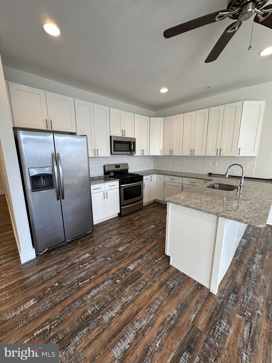 2206 North Front Street, Unit 2B Philadelphia, PA 19133 - Photo 19 of 28 a kitchen with stainless steel appliances granite countertop a sink a stove a refrigerator with white cabinets and wooden floor