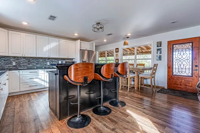 a kitchen with stainless steel appliances granite countertop a sink a stove and wooden floors
