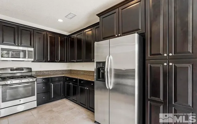 a kitchen with granite countertop a refrigerator and a stove top oven