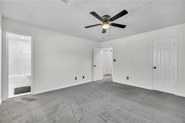an empty room with ceiling fan and windows