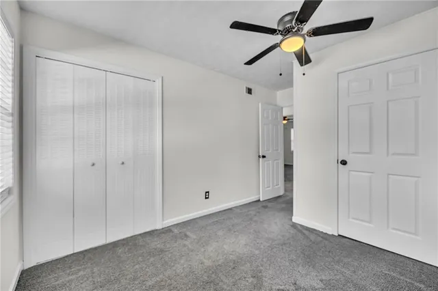 an empty room with closet and a chandelier fan