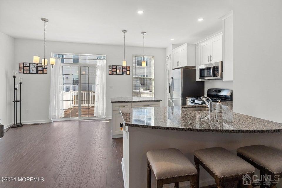 304 Discovery Road, Unit 1804 Brick, NJ 08723 - Photo 16 of 48 a kitchen with stainless steel appliances granite countertop a kitchen island hardwood floor and a refrigerator