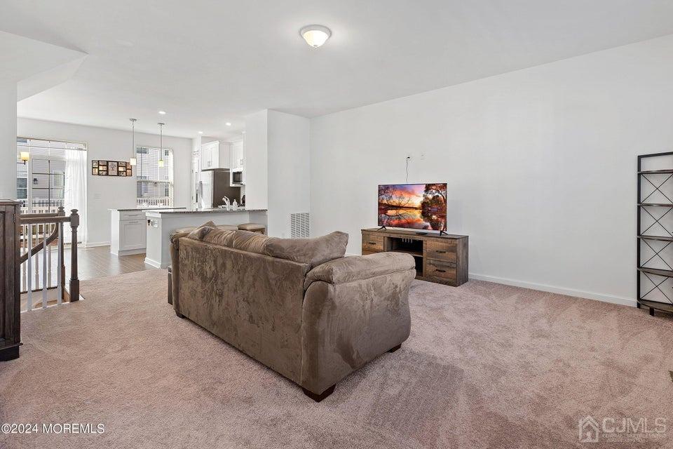 304 Discovery Road, Unit 1804 Brick, NJ 08723 - Photo 22 of 48 a living room with furniture a flat screen tv and kitchen view