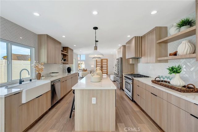 a large kitchen with kitchen island a large counter top space a sink stainless steel appliances and cabinets