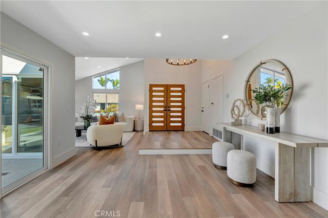 a kitchen with stainless steel appliances kitchen island granite countertop a sink a stove a refrigerator cabinets and a dining table with wooden floor