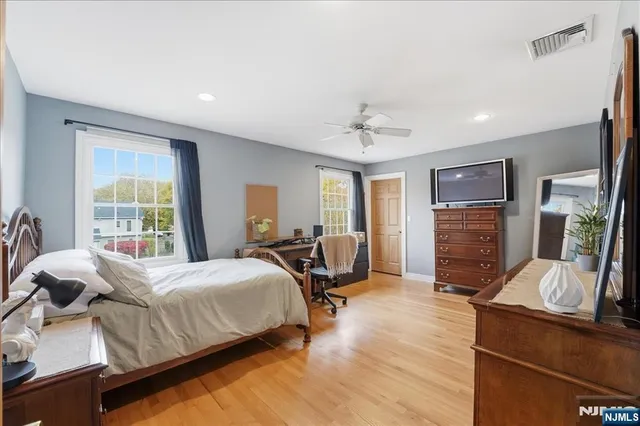 a bedroom with a bed a flat tv screen and dresser