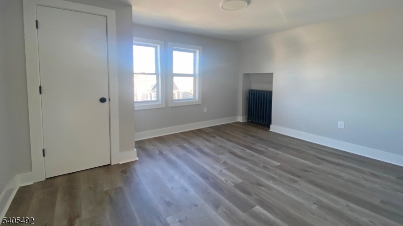 144 Maple Avenue Irvington, NJ 07111 - Photo 10 of 12 an empty room with wooden floor and windows
