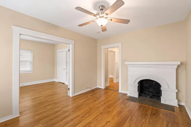 a view of a livingroom with a fireplace a chandelier fan and wooden floor