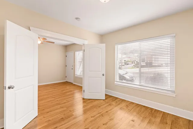a view of an empty room with wooden floor and a window