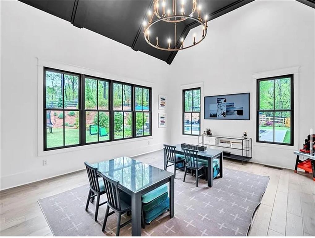 a dining room with wooden floor a chandelier a wooden table and chairs