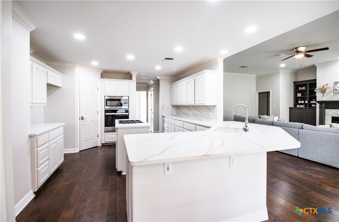 202 Ridge View Victoria, TX 77904 - Photo 14 of 41 a large kitchen with kitchen island a sink a stove a refrigerator and white cabinets with wooden floor