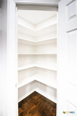 an empty room with wooden floor ceiling fan and windows