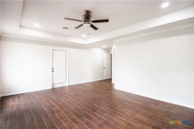 a view of a hallway with wooden floor and a ceiling fan