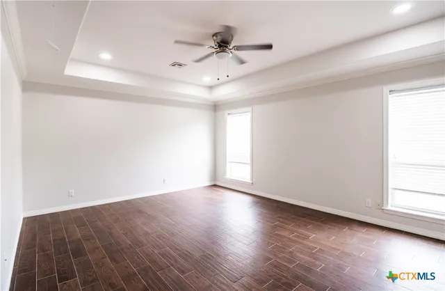 an empty room with wooden floor and windows