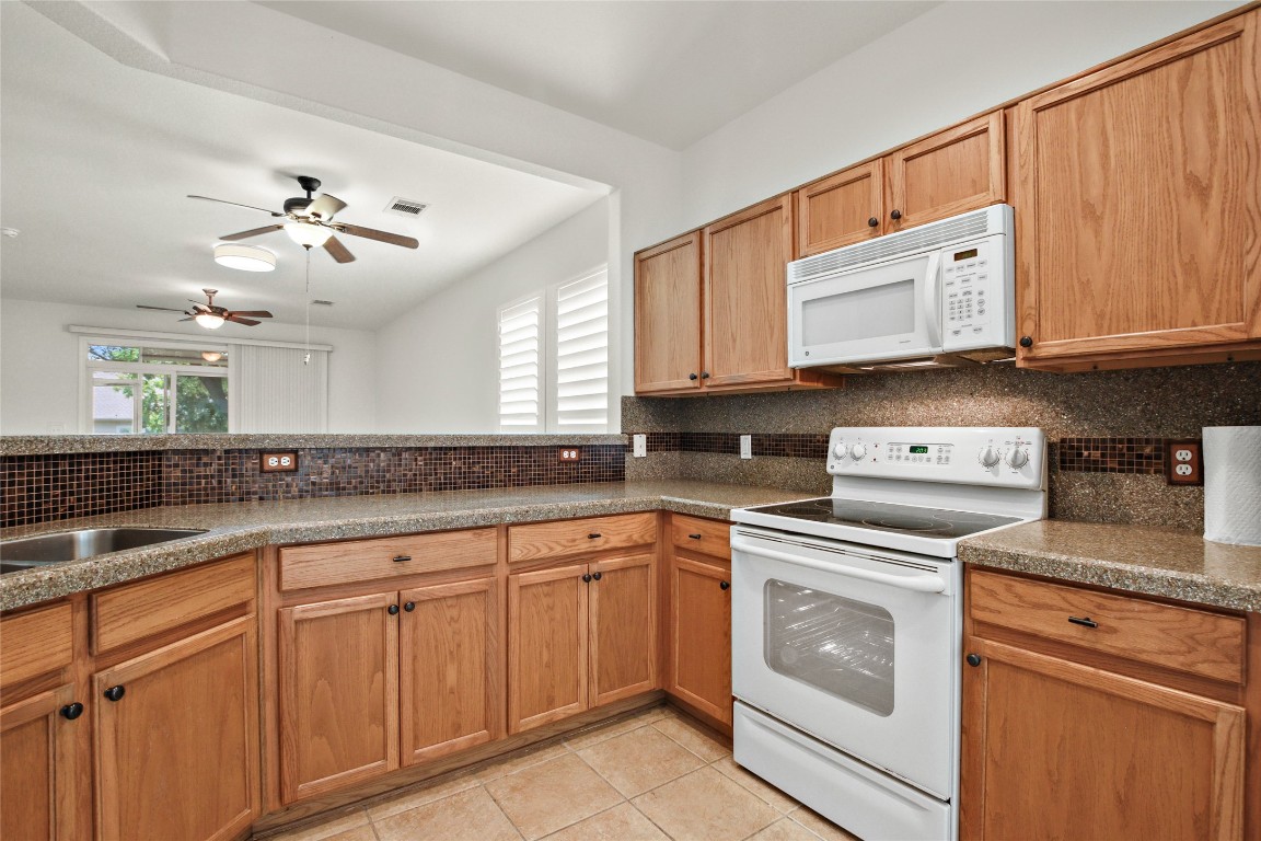 119 Hampton Circle Georgetown, TX 78633 - Photo 14 of 28 Kitchen with white appliances, tasteful backsplash, light tile patterned floors, ceiling fan, and healthy amount of natural light